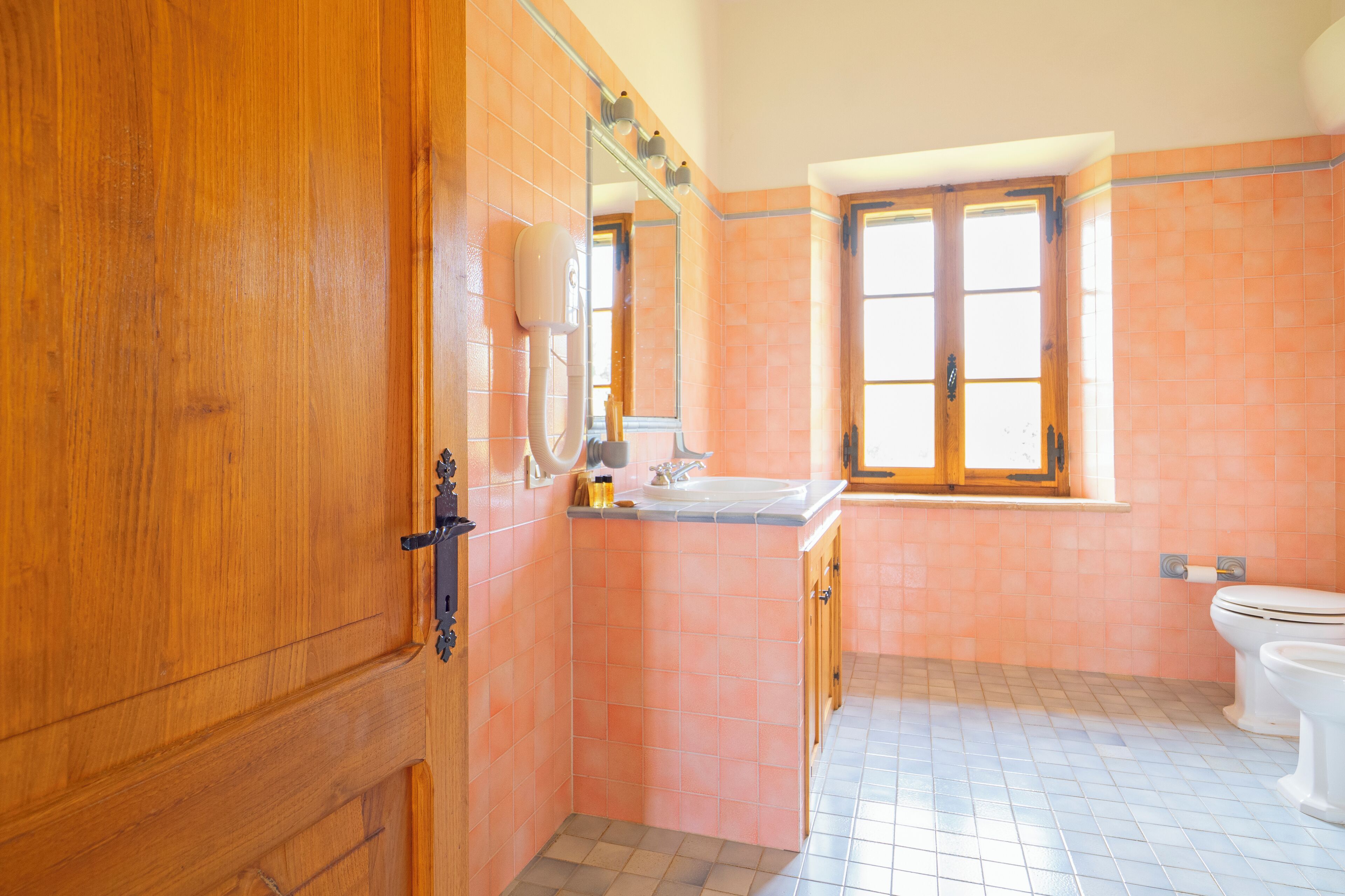 A bathroom with wooden cabinetry, a sink, and a toilet.