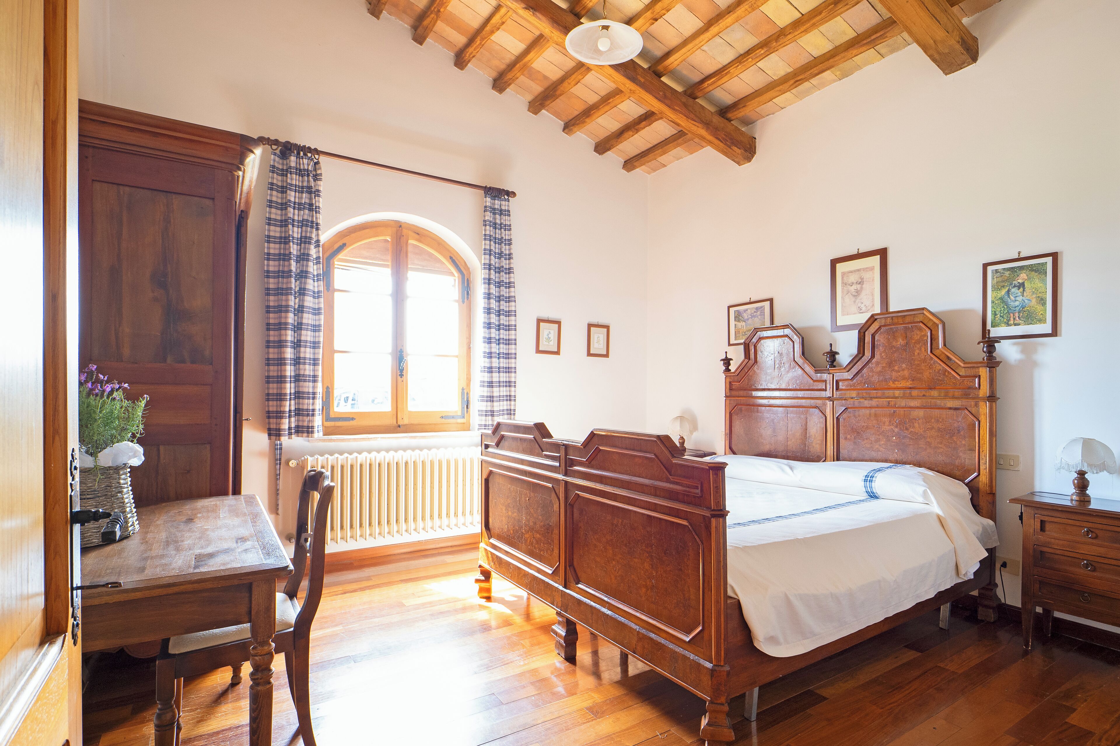 Una camera da letto con un letto e una scrivania in legno, una sedia e una finestra con tende.