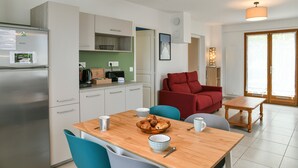 Una cocina moderna con armarios blancos, un refrigerador de acero inoxidable y un comedor con mesa de madera y sillas azules.
