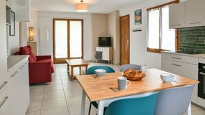 Una cocina moderna con comedor, un sofá rojo y una televisión.
