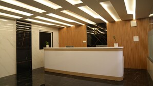 Un área de recepción de diseño moderno, con mostrador de mármol, paneles de madera e iluminación lineal en el techo.