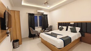 Una habitación de hotel moderna con una cama de madera, un escritorio con una silla, un televisor y un equipo de aire acondicionado.
