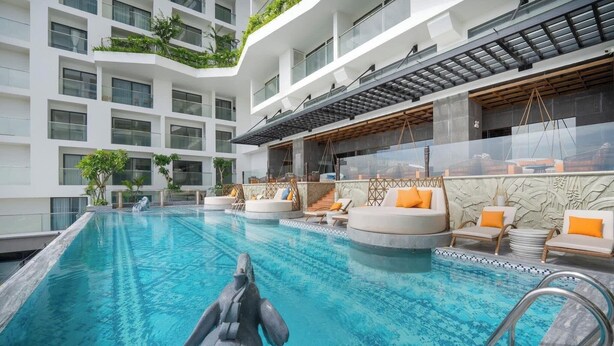 Un hotel moderno con una gran piscina cubierta, varias zonas de estar y vistas a la arquitectura del edificio.