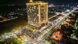 Un hotel de gran altura con varios pisos, fachada iluminada y una calle concurrida al frente.