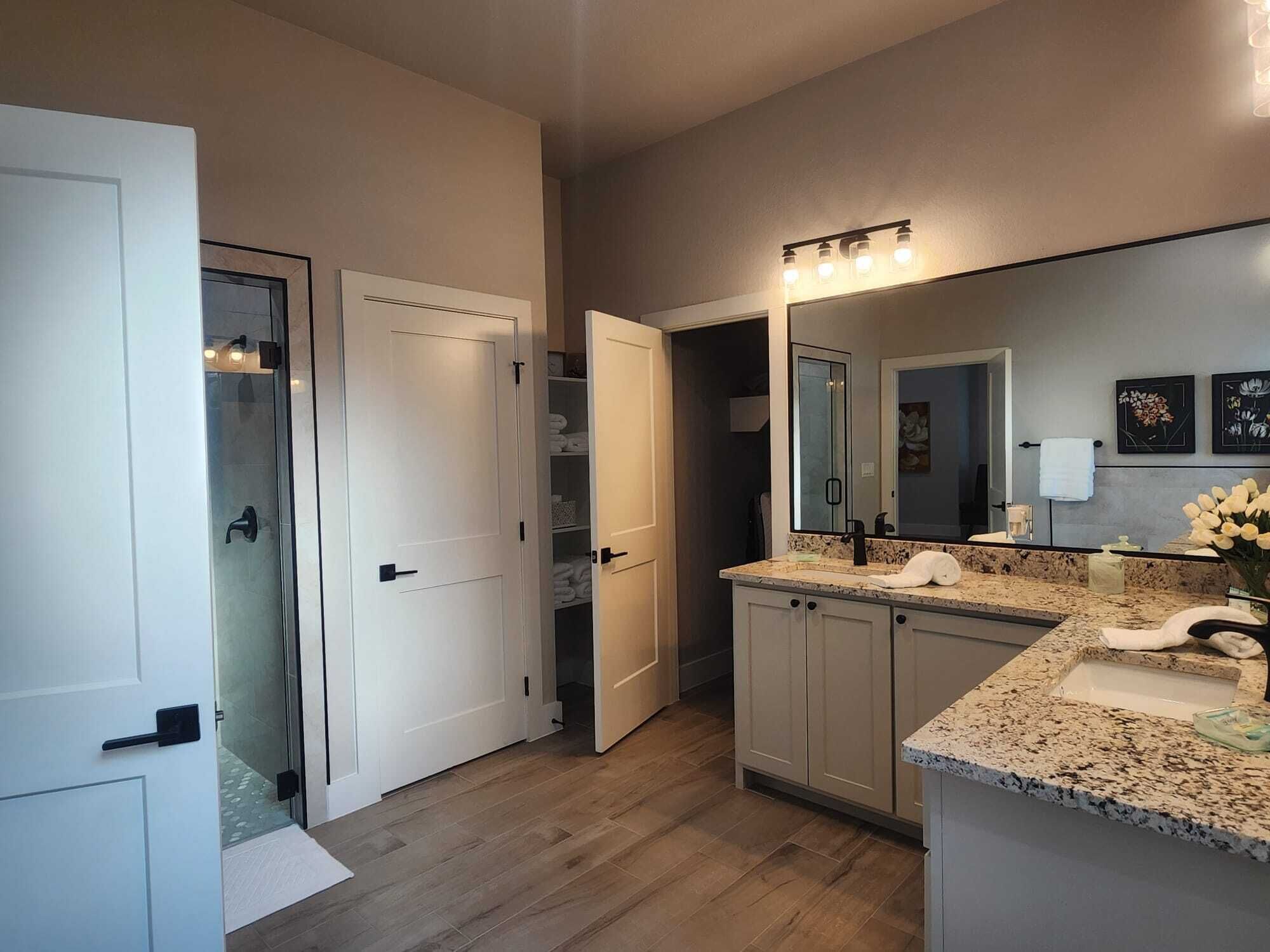 A modern bathroom with a large mirror, a vanity with a sink, and a shower area.