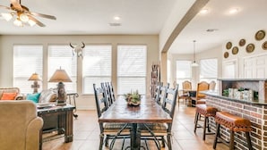 A spacious dining area with a long wooden table, multiple chairs, and a brick accent wall. - Charming house with AC and fitness room in enjoyable Fort Worth (Fort Worth)