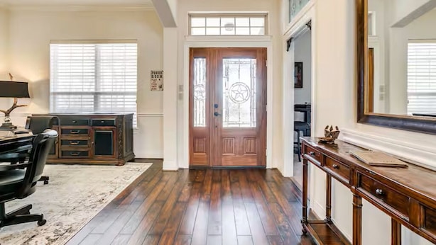 A spacious entryway with a wooden floor, a desk with a chair, a large mirror, and a door with a decorative glass panel. - Charming house with AC and fitness room in enjoyable Fort Worth (Fort Worth)
