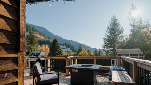 A wooden deck with a grill, a table, and a chair. - Character 3-bdr Newly Reno'd Modern OceanSky Lodge (Britannia Beach)