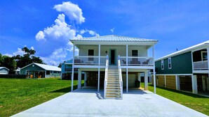 A two-story house with a covered front porch and a staircase leading to the upper level. - Brand New Spacious 5BR, 4BA house Built Aug 25, 85 in TV, GameRoom, New Special (Gulfport)