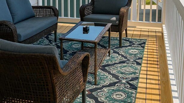 A covered outdoor seating area with wicker furniture and a patterned rug, overlooking a beach and a house. - Brand New Spacious 5BR, 4BA house Built Aug 25, 85 in TV, GameRoom, New Special (Gulfport)