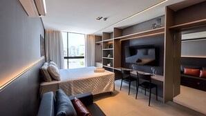 Una habitación de hotel moderna con cama, zona de estar, televisor y armario empotrado.