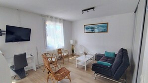 Un saló modern amb televisió plana, cadires de vimet, un sofà i una taula de centre.