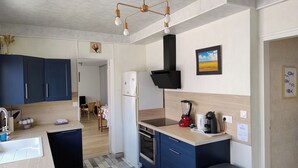 Una cuina compacta amb forn integrat, nevera, rentapelats i una encimera amb cafetera i batedora.