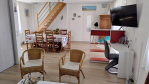Un saló amb zona de menjador, escala, televisió de pantalla plana i prestatgeries.