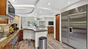 Una cocina moderna con una isla central, electrodomésticos de acero inoxidable y piso de madera.