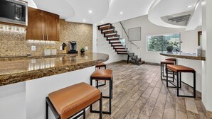 Una cocina moderna con una isla curva, armarios de madera y microondas integrado.