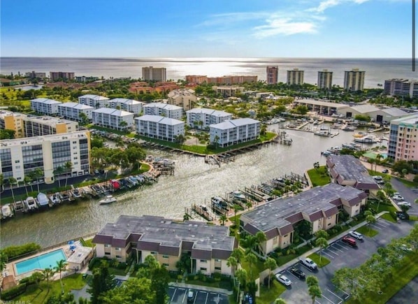 A coastal residential area with multiple apartment buildings, a marina, and a view of the ocean.