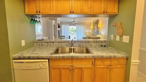 A kitchen with wooden cabinets, a double sink, and a dishwasher.