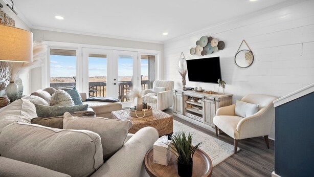 A spacious living room with a large TV, comfortable seating, and a view through the glass doors. - Oceanfront Villa, Private Pool, Beautiful Beach Views - 410 Captain John Fripp (Fripp Island)