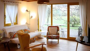 Un salon confortable avec un canapé, un fauteuil, une table et une grande fenêtre agrémentée de rideaux.