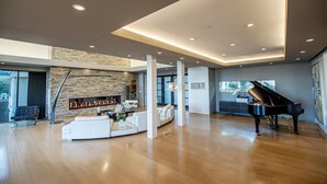 A spacious living area with a stone fireplace, a grand piano, and a modern sofa set. - Fantastic 7-bedroom house with AC in Los Altos Hills (Los Altos Hills)
