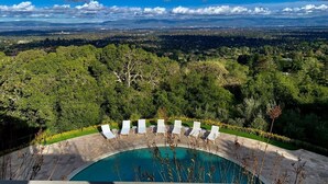 A pool with white lounge chairs, surrounded by lush greenery and a view of distant landscapes. - Fantastic 7-bedroom house with AC in Los Altos Hills (Los Altos Hills)