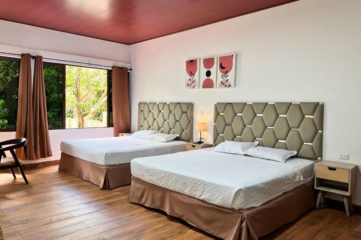 A hotel room with two beds, a desk, and a window with curtains.
