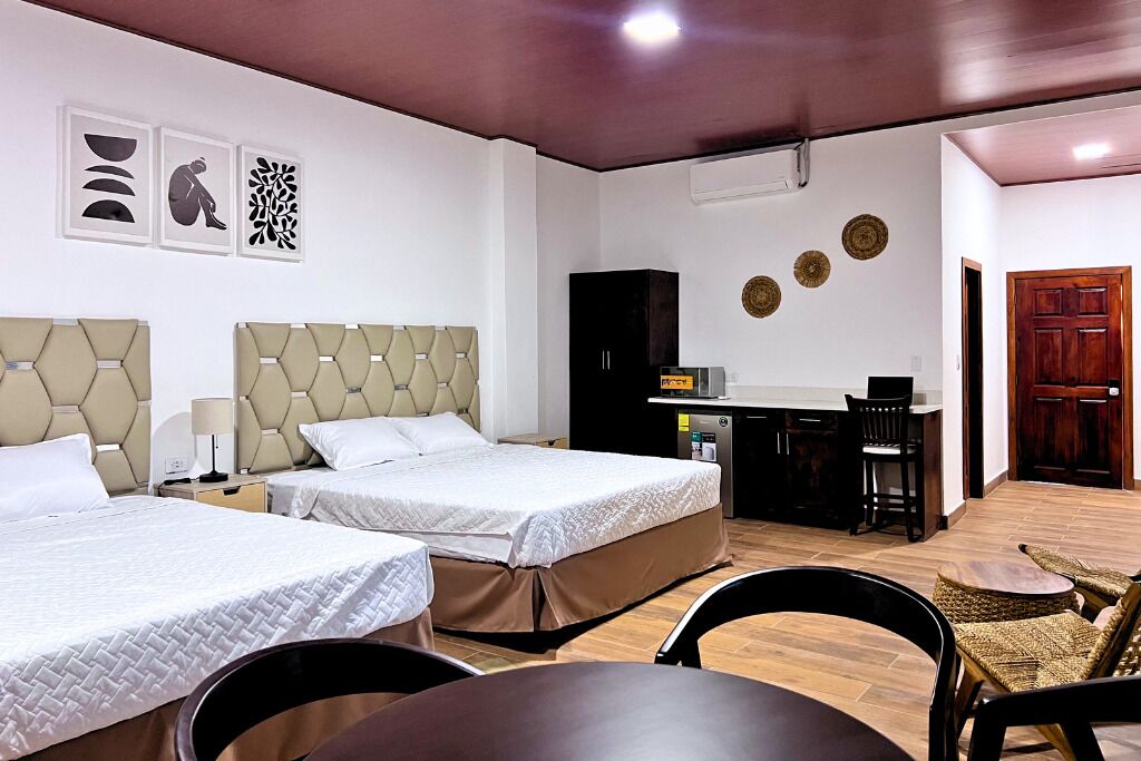 Een hotelkamer met twee bedden, een bureau en een eethoek.