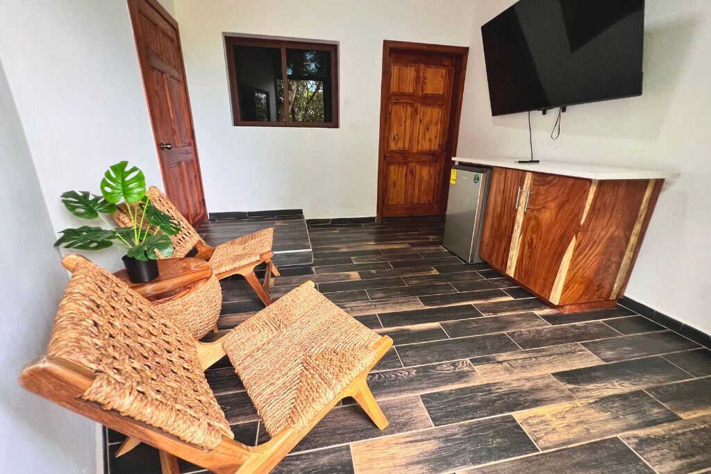 A small room with a sofa, a coffee table, a TV mounted on the wall, and a wooden cabinet.