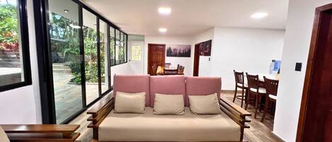 Una sala de estar moderna con un sofá, mesitas de madera y un comedor con sillas y una mesa.