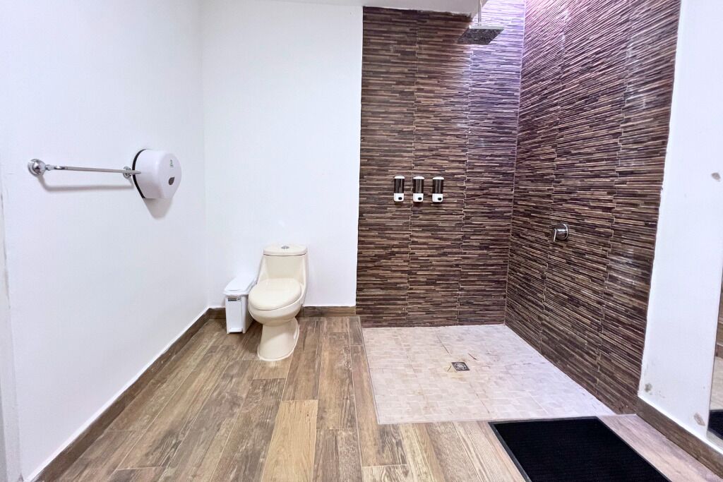 Een badkamer met een toilet, een bidet en een douchegedeelte met een geribbelde wand.