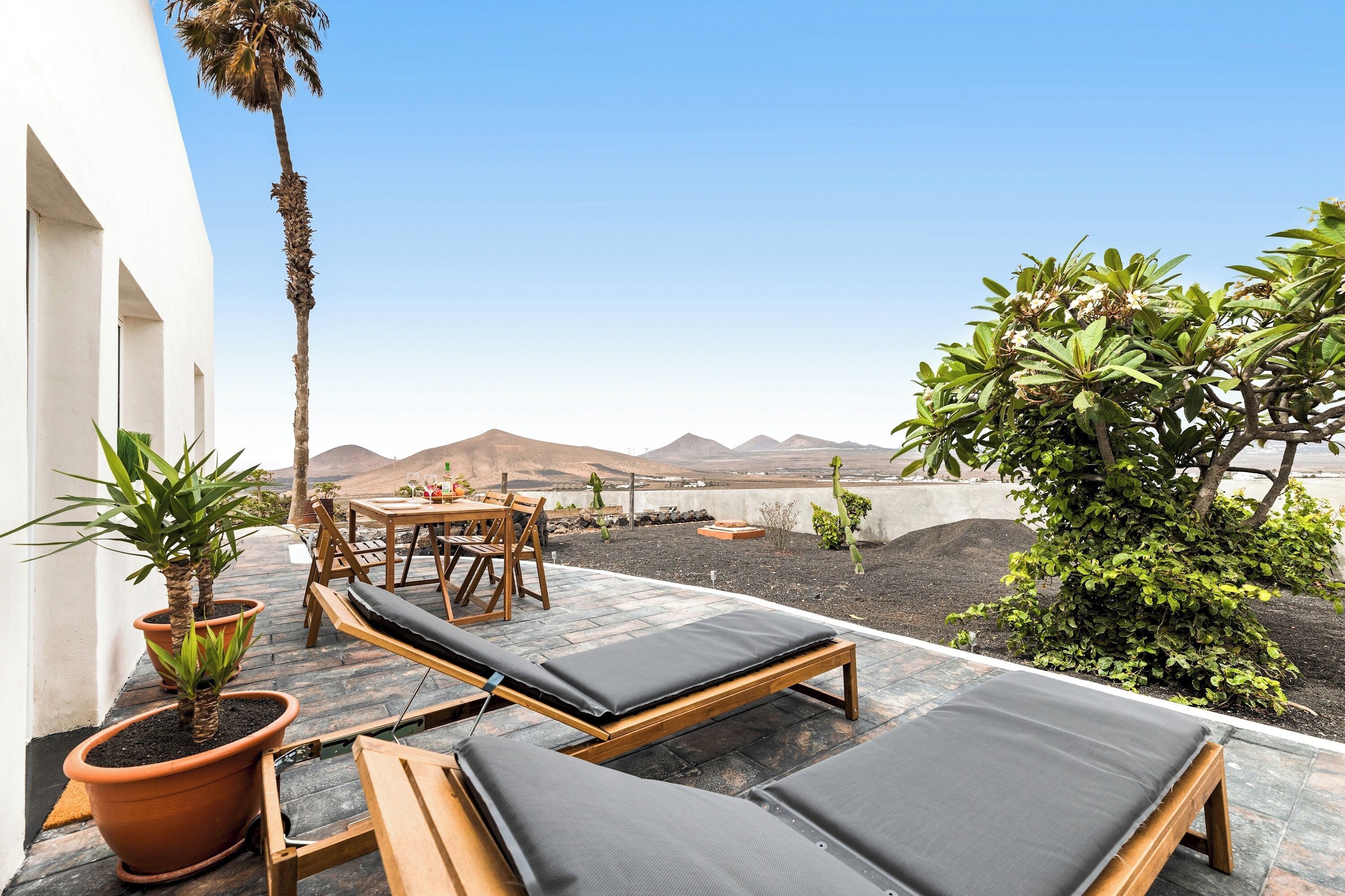 A patio with lounge chairs, a table, and potted plants.