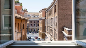 A narrow street with buildings on either side, a clear sky, and parked cars. - TreasureRome Forum Rooftop Terrace Colosseum area • 2BR Duplex (Rome)