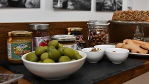 Uma mesa com diversos alimentos, incluindo azeitonas, potes de conservas e pão.