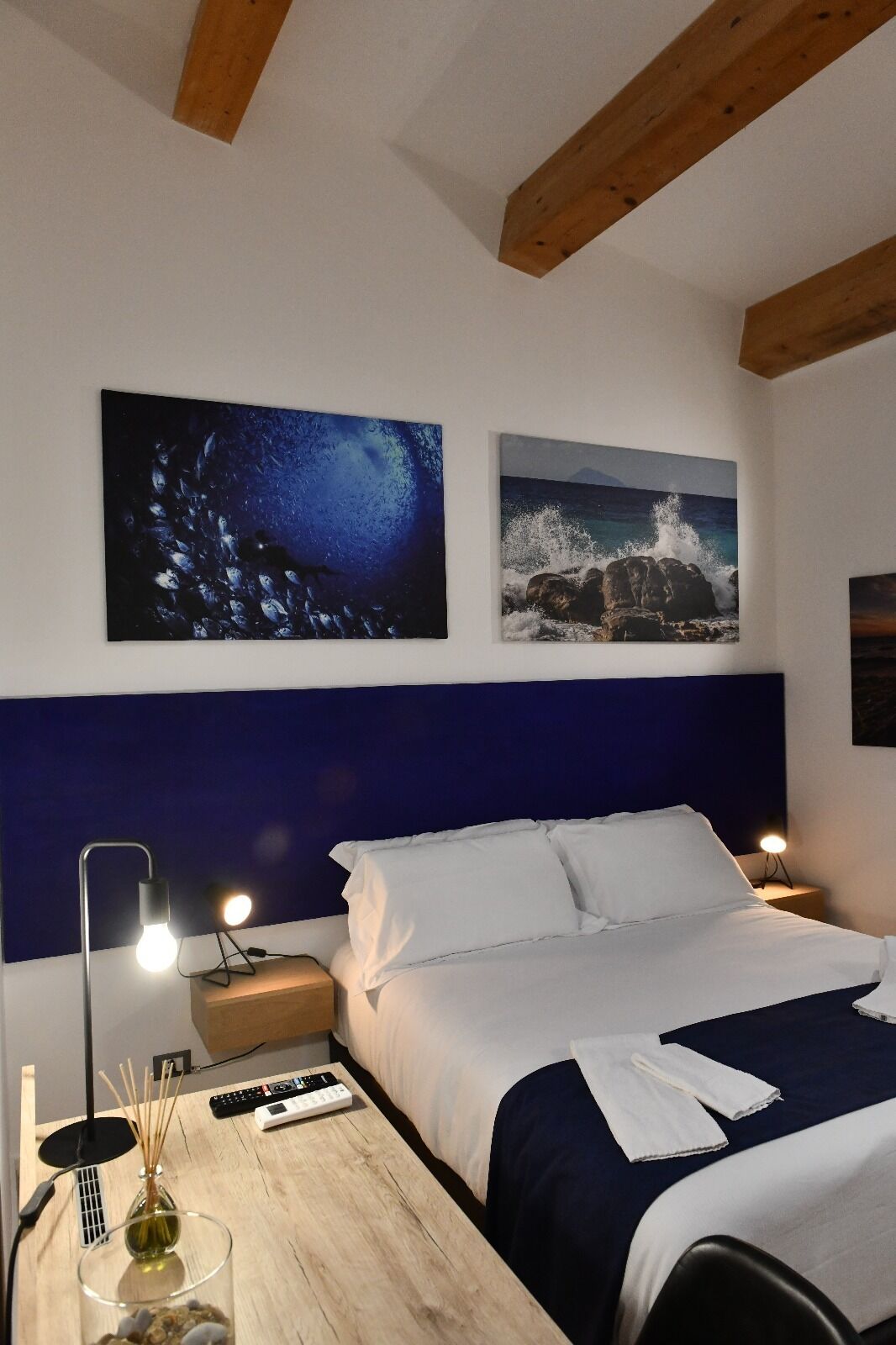 Una habitación de hotel con cama, mesitas de noche, un escritorio y obras de arte en las paredes.