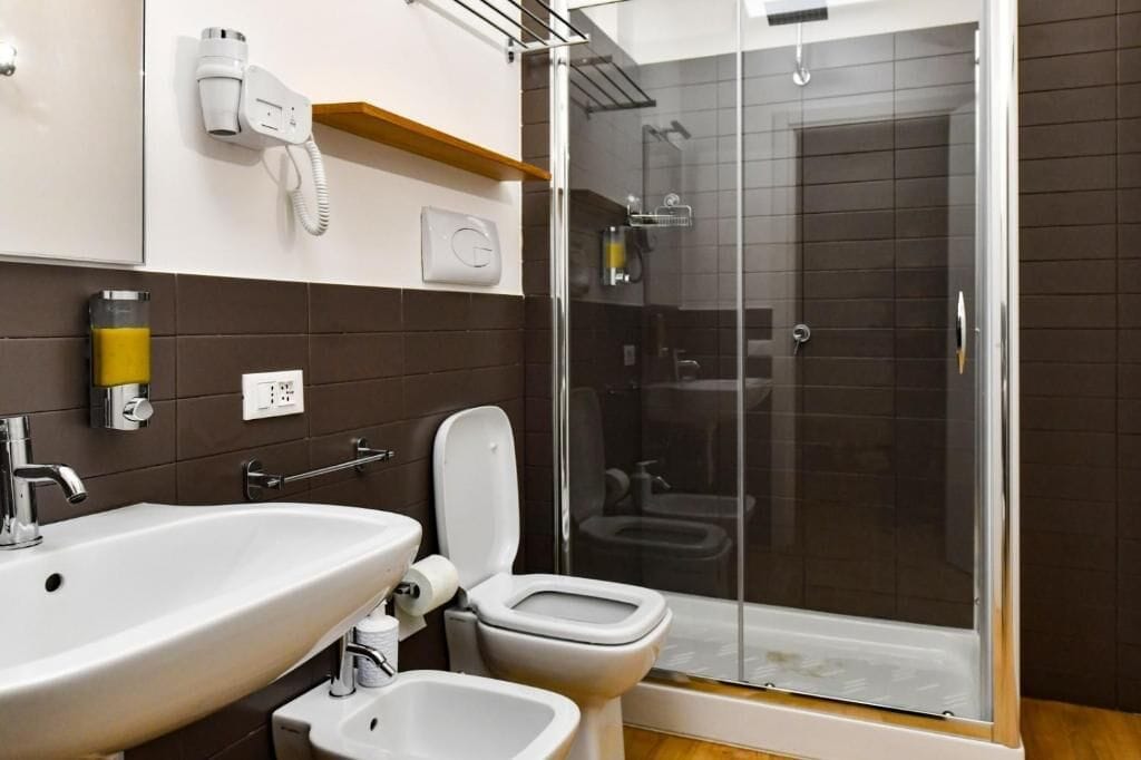 A modern bathroom with a sink, toilet, bidet, and a glass-enclosed shower area.