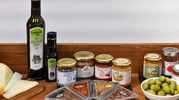 Diversos alimentos como aceite de oliva, queso y embutidos sobre una superficie de madera.
