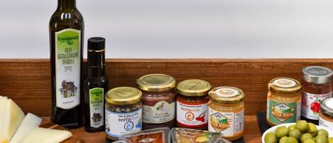 A variety of food items including olive oil, cheese, and preserved meats on a wooden surface.