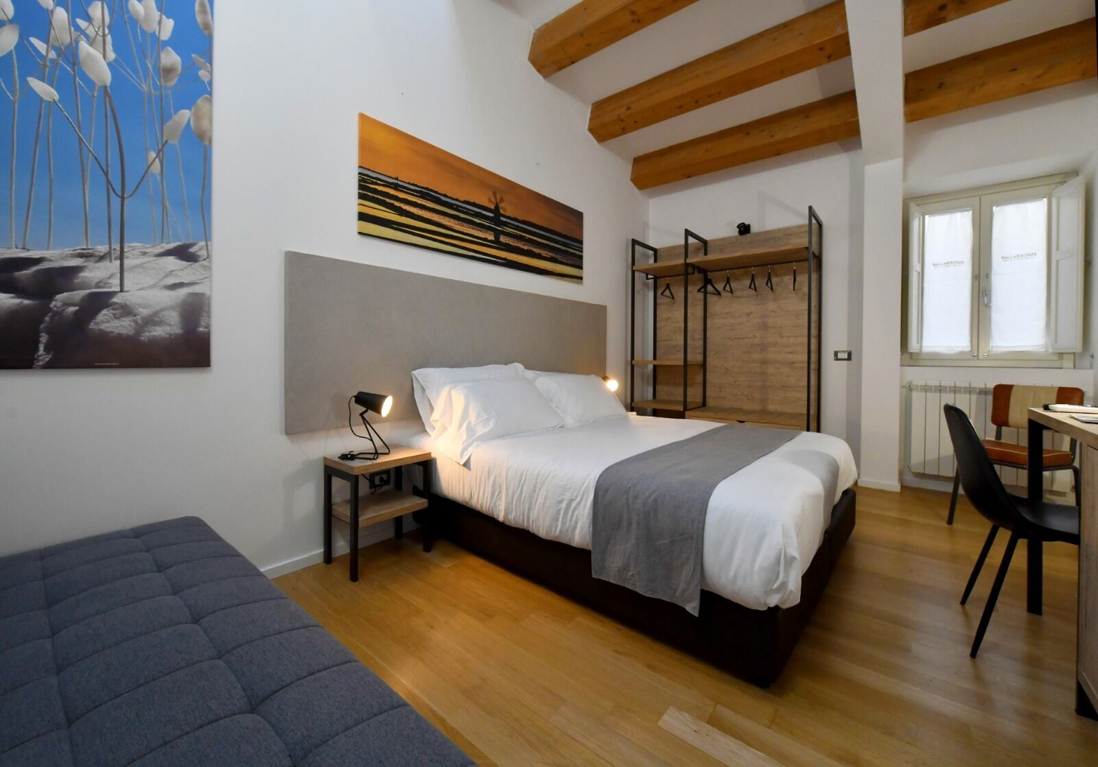A bedroom with a bed, bedside table, lamp, and a painting on the wall.
