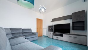 Una sala de estar moderna con un sofá seccional gris, un televisor de pantalla plana y un mueble empotrado para entretenimiento.