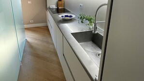 Une cuisine moderne avec un évier en acier inoxydable, une planche à découper en bois et une plante en pot.