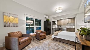 A modern bedroom with a large bed, two leather sofas, a small table, and a large window. - Lake Oswego Quiet Ground Level Condo Private Entrance - Pet Friendly! (Lake Oswego)