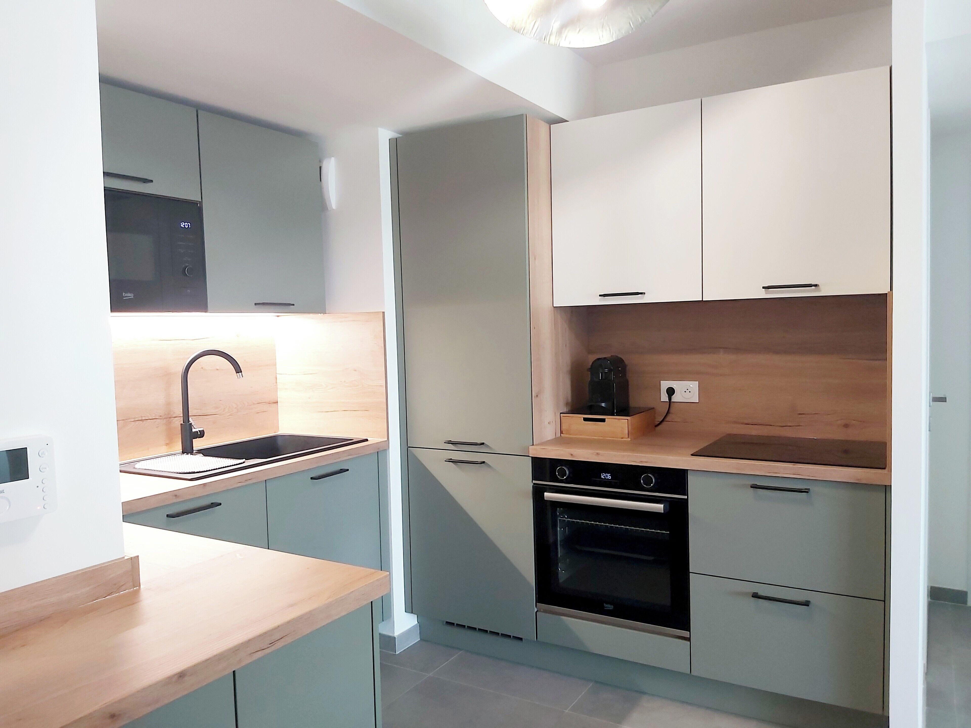 Een moderne keuken met een inbouwoven, een magnetron en een spoelbak met een kraan.