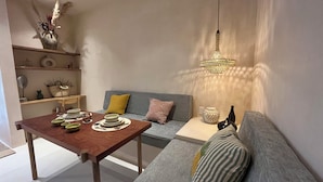 A modern living room with a wooden dining table, a grey sofa with patterned cushions, and a hanging light fixture. - Aflora Tulum (Tulum)