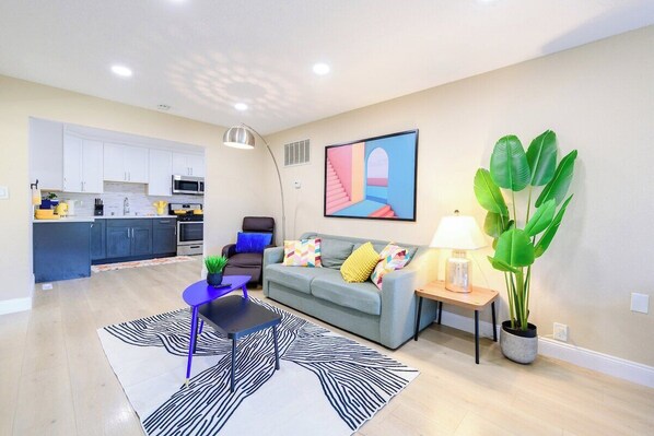 Una sala de estar moderna con un sofá, una mesa de centro, una lámpara y una planta grande.