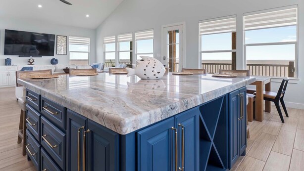 A spacious kitchen with a large island, dark blue cabinetry, and a ceiling fan. - Unwind on the Bay- Fishing, Pool, Tennis, Basketball courts & Kids' Playground (Palacios)