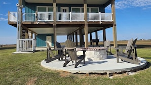 A two-story house with a balcony, outdoor seating area, and a fire pit. - Unwind on the Bay- Fishing, Pool, Tennis, Basketball courts & Kids' Playground (Palacios)