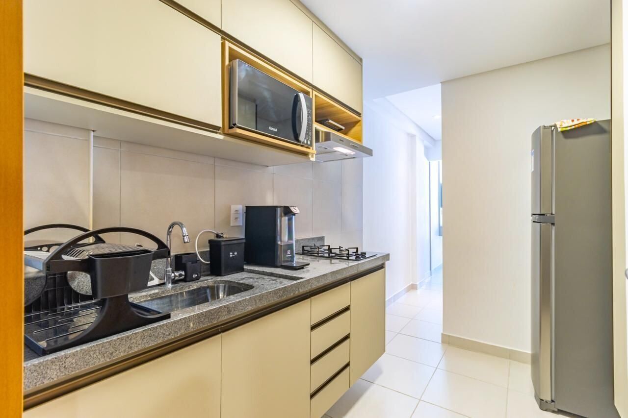 Une cuisine moderne équipée d’un four à micro-ondes encastré, d’une cuisinière à gaz et d’un réfrigérateur en acier inoxydable.