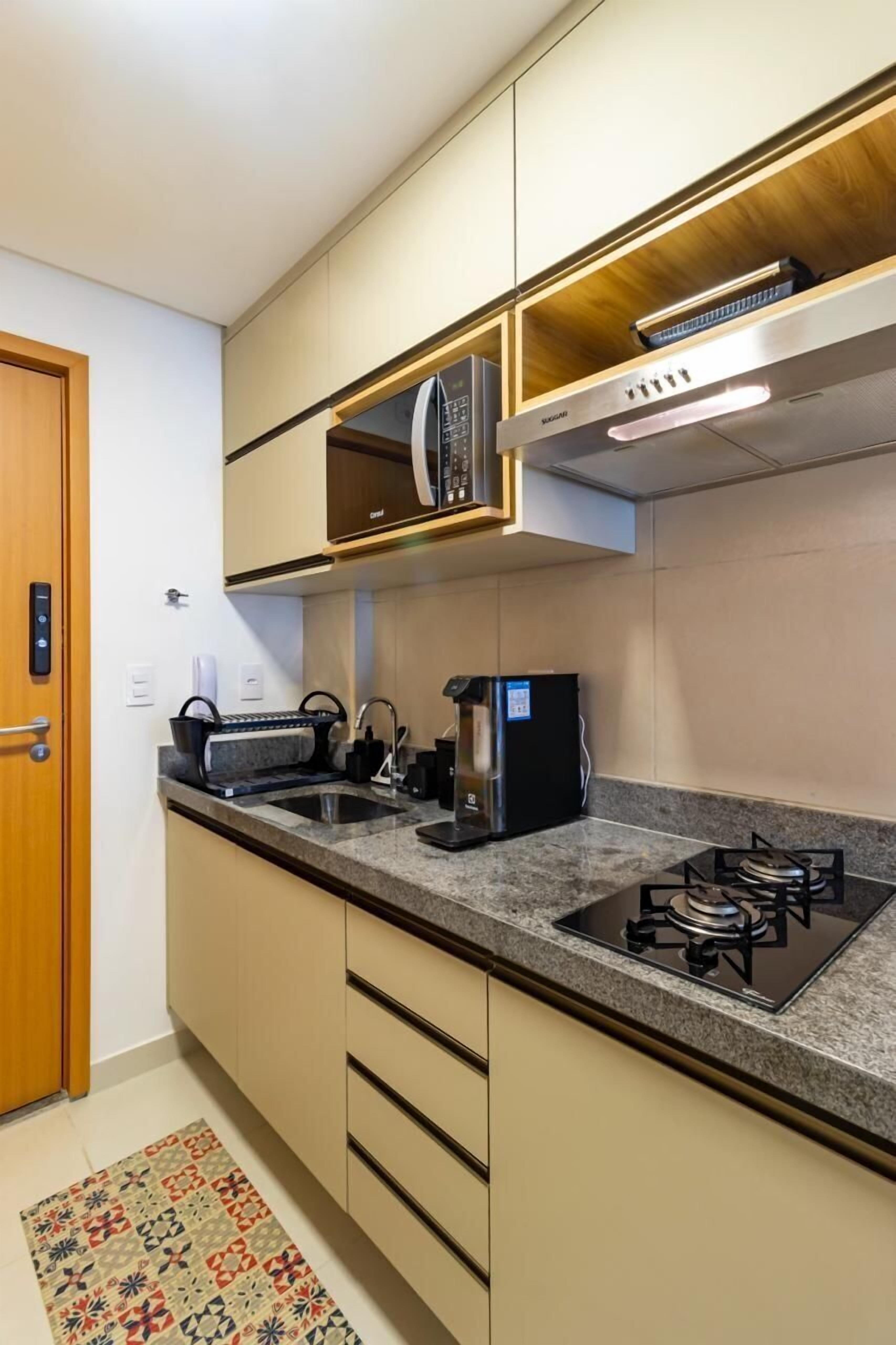 Een moderne keuken met inbouwapparatuur, een magnetron, een waterkoker en een gasfornuis.