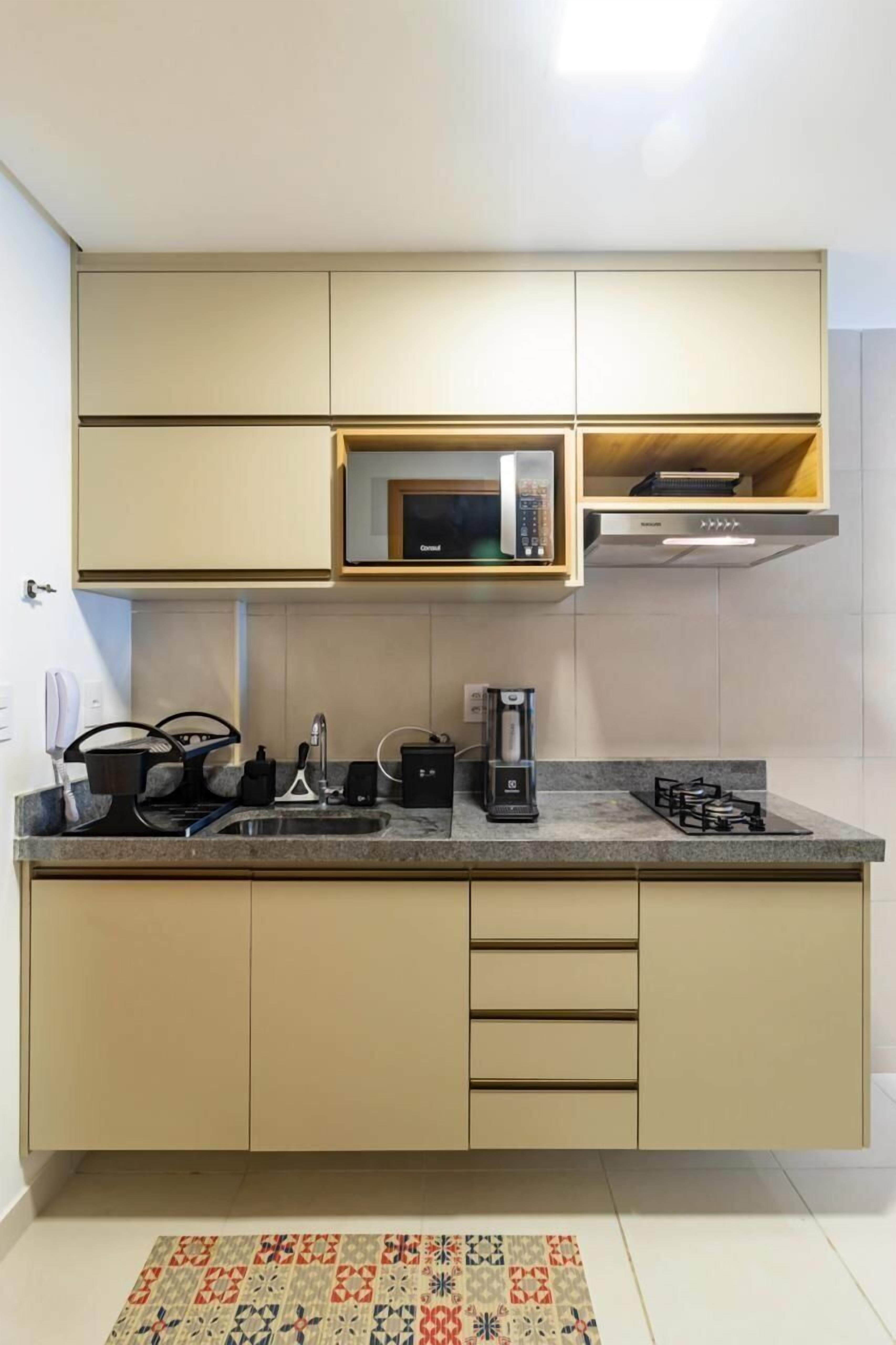 A compact kitchen with a microwave, coffee maker, and gas stove.